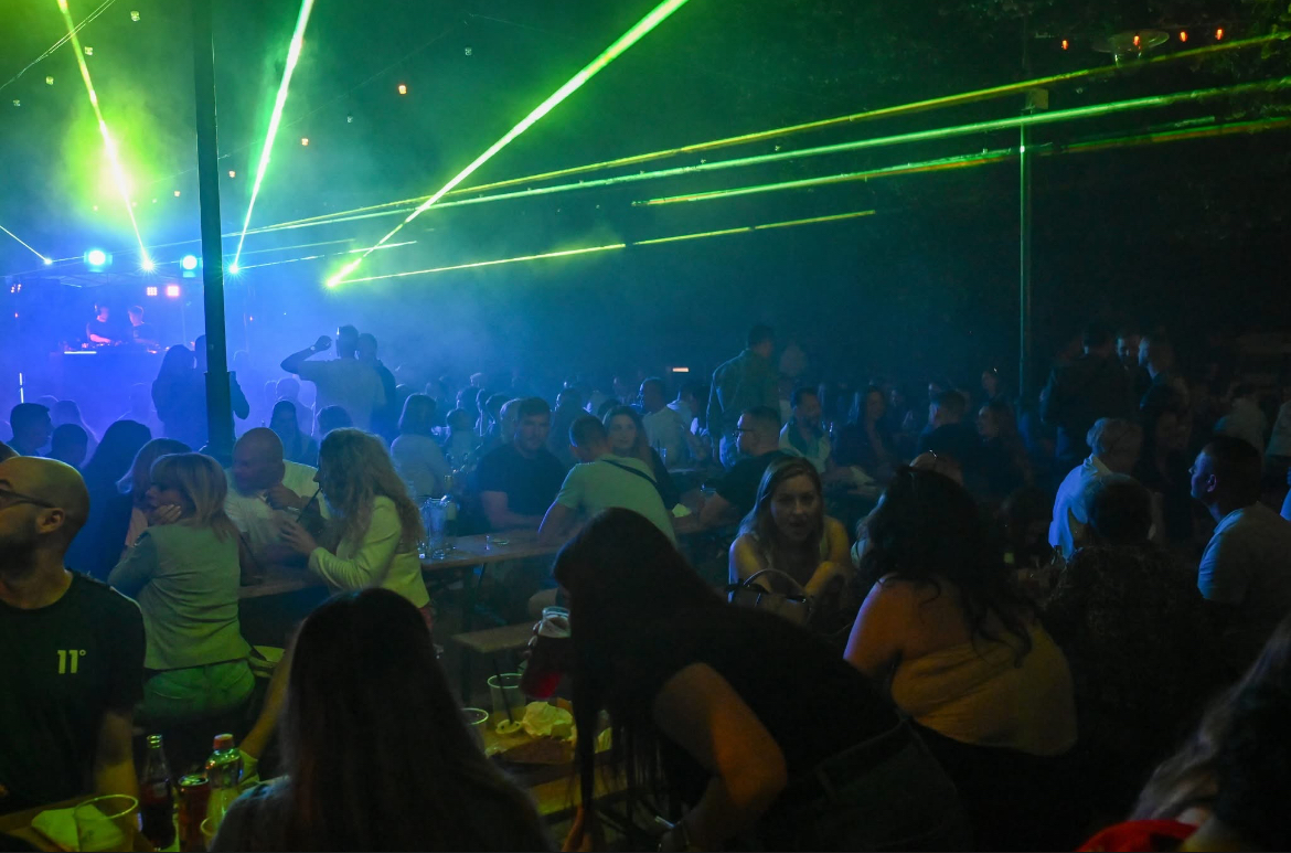 Outdoor event crowd illuminated by green overhead laser architecture
