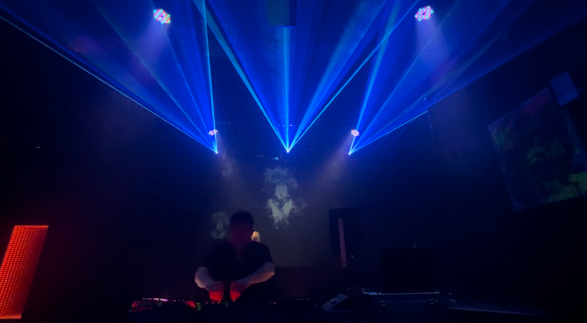 Club DJ booth with blue overhead laser fan and lighting fixtures