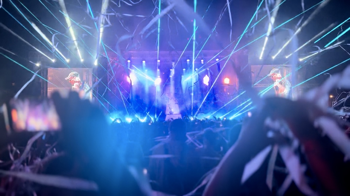Festival stage illuminated by blue laser beams and confetti
