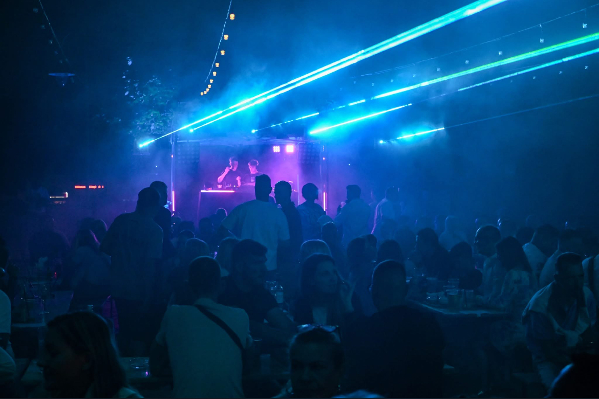 Outdoor evening crowd immersed in overhead cyan laser beams